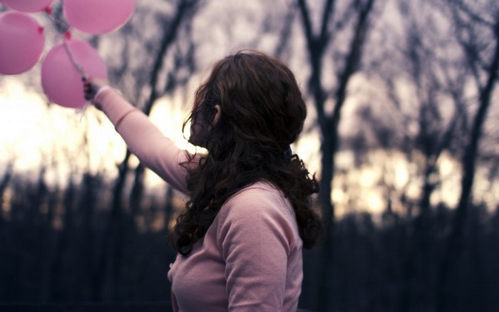 Girl holding pink balloons in a forest