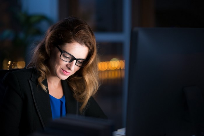 Woman wearing glasses working on a computer at night