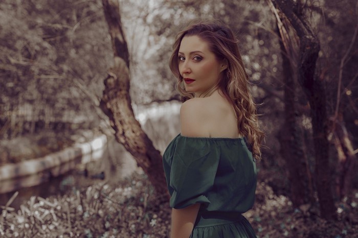 Woman in green off-the-shoulder dress in forest