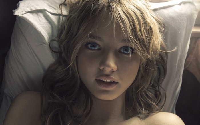 Young woman with blue eyes lying on a pillow