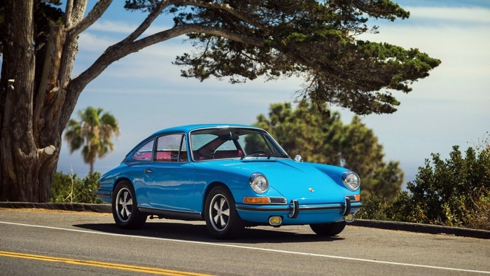 Blue Porsche 911 parked on a road under a tree
