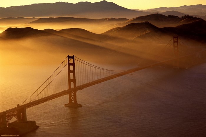 Golden Gate Bridge at sunrise with fog and mountains