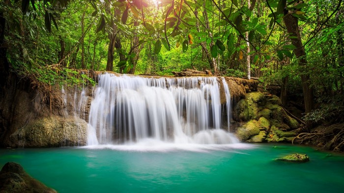 Waterfall in a lush green forest with turquoise water