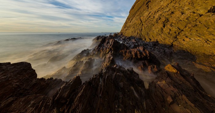 Rocky coast with misty sea and dramatic cliff at sunrise