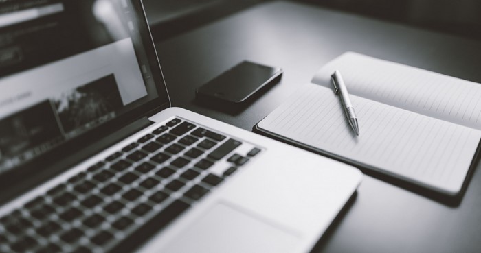 Laptop, smartphone, and notebook with pen on desk