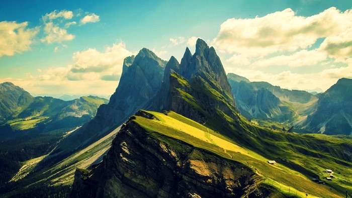 Sunlit mountain range with green meadows and sharp peaks
