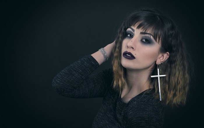 Woman with dark makeup and cross earring