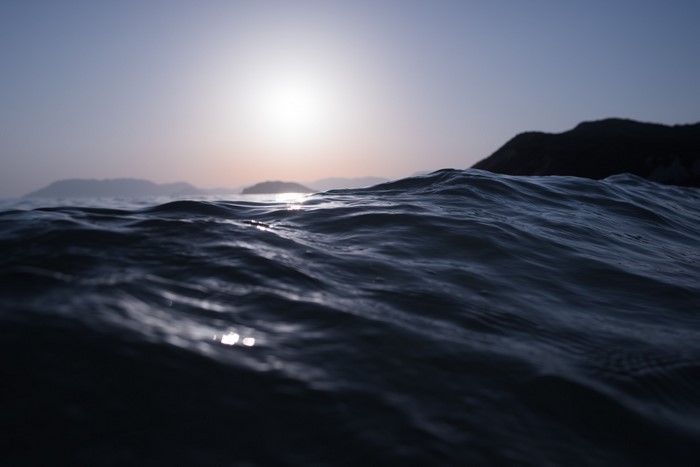 Ocean waves at sunset with distant islands