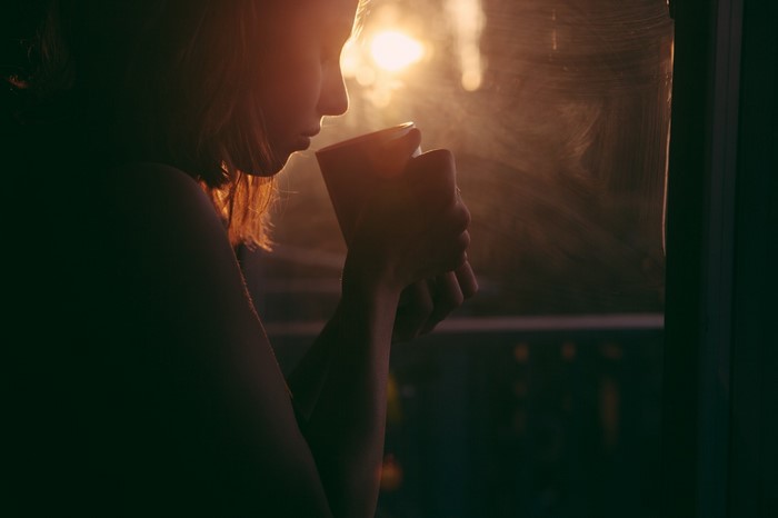 Woman holding a mug in sunlight by the window
