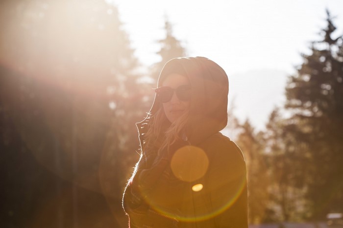 Woman in a hood with sunglasses in sunlight