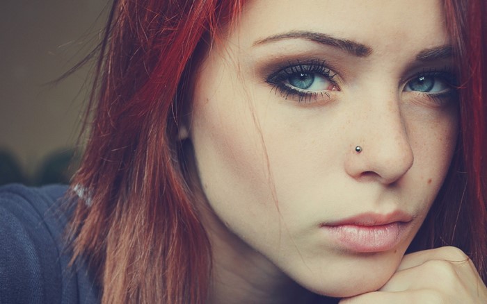 Close-up portrait of a young woman with red hair and blue eyes