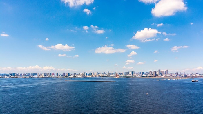 City skyline across a wide blue bay under a cloudy sky