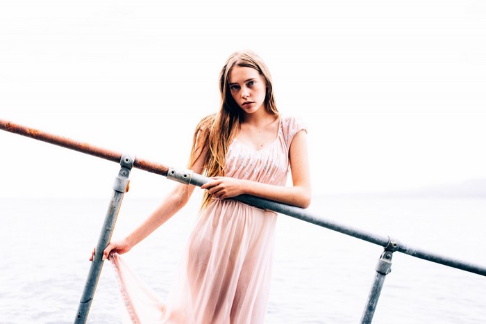 Woman in pink dress posing by railing