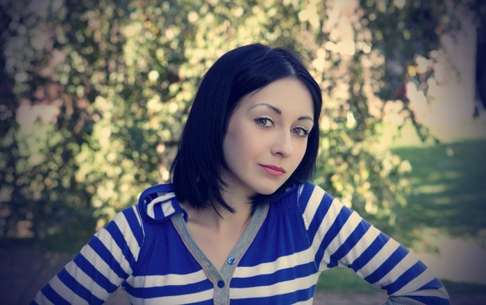 Woman with dark hair in a striped shirt outdoors