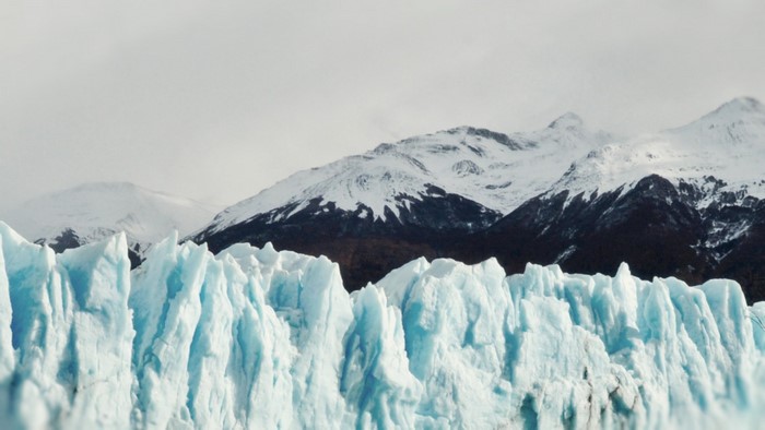 Glacier and snow-capped mountains under a cloudy sky