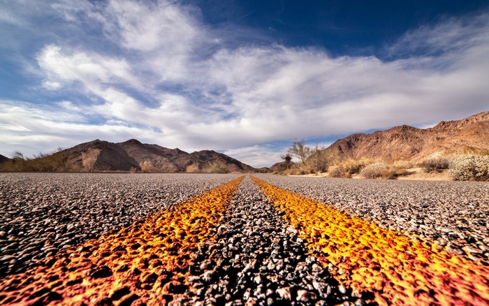 Desert road with mountains and clouds
