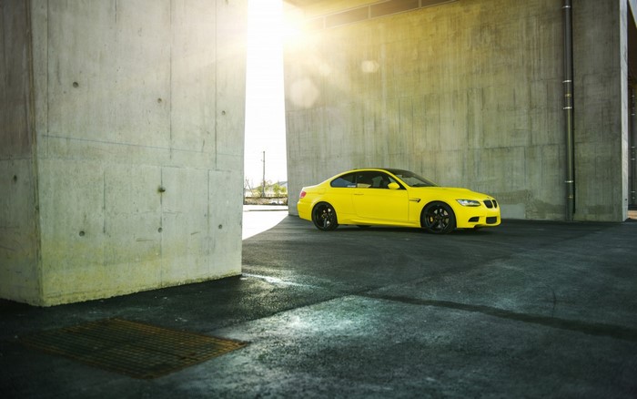Yellow BMW sports car parked under concrete structure