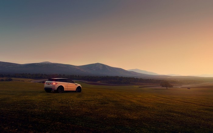 White Range Rover Evoque on a grassy field at sunset