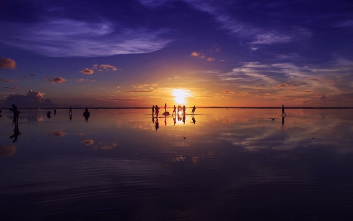 People silhouetted against a sunset over the sea