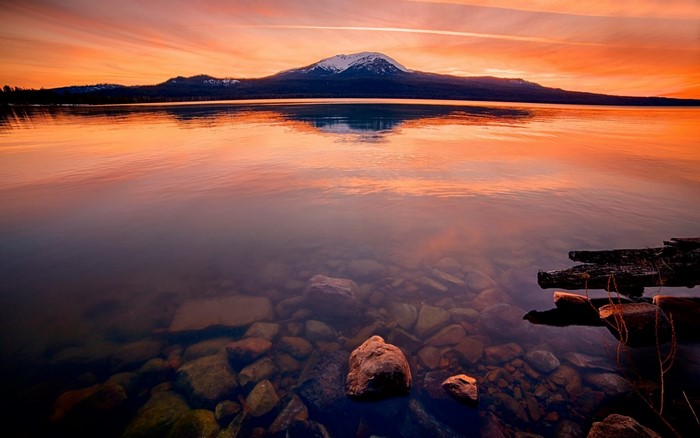 Mountain lake at sunset with rocky shore