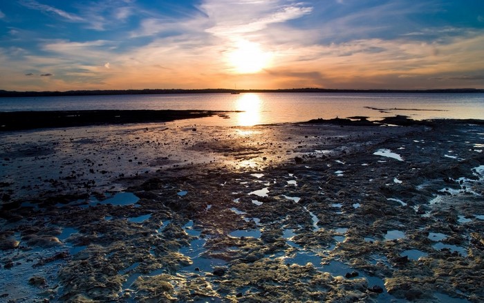 Sunset over the sea with rocky shore and clouds