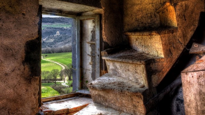 Abandoned stone staircase overlooking a rural landscape with a distant castle