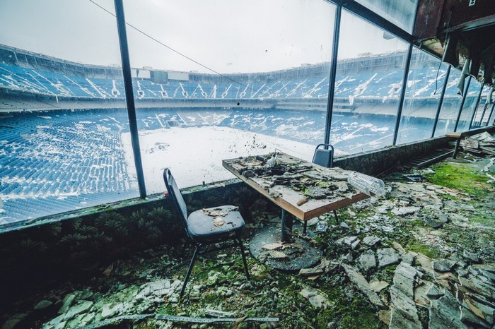 Abandoned stadium interior with debris and snow-covered field