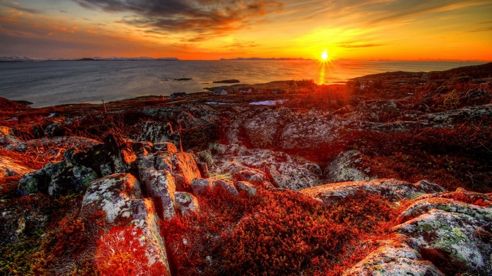 Sunset over rocky coast with ocean and mountains