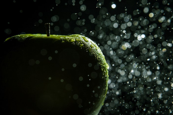 Green apple with water drops and bokeh