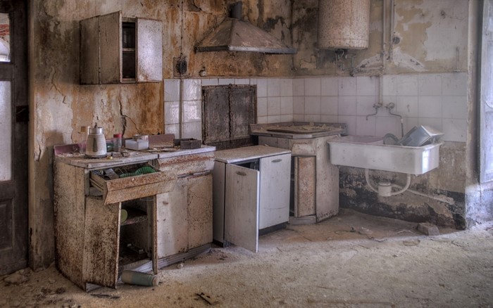 Abandoned kitchen with old appliances and peeling walls