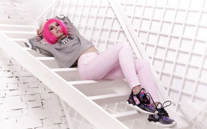 Woman with pink hair on white stairs wearing pink pants and sneakers