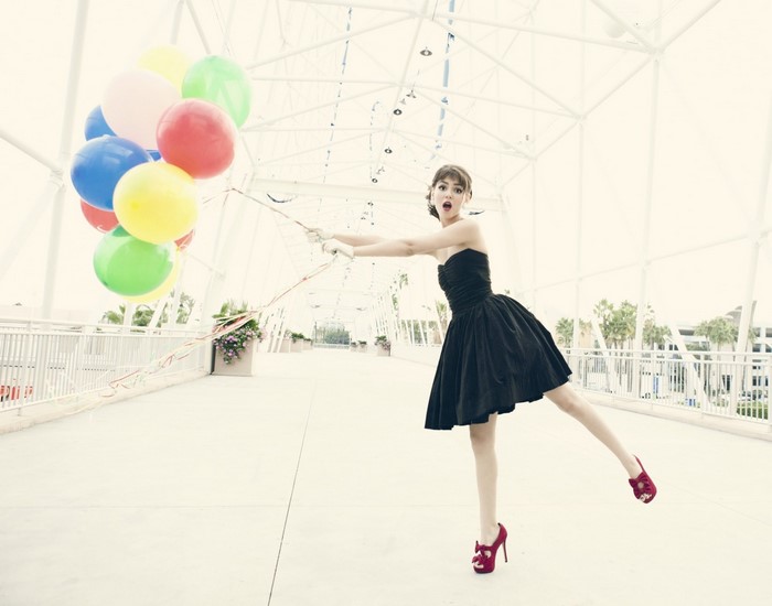 Woman in black dress holding balloons