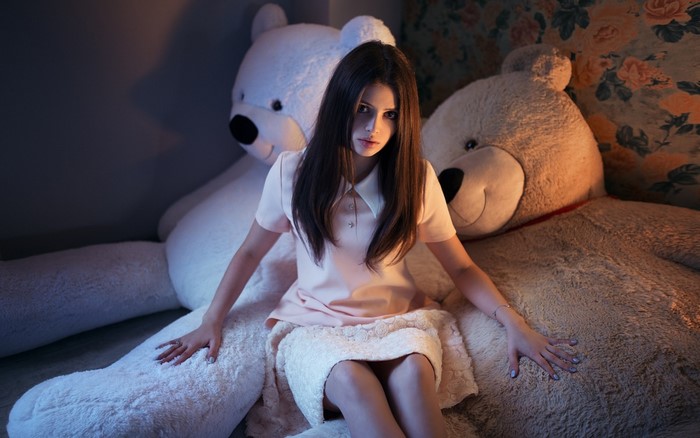 Woman sitting between two large teddy bears