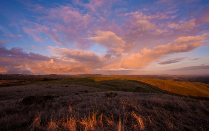Sunset over rolling hills with dramatic clouds
