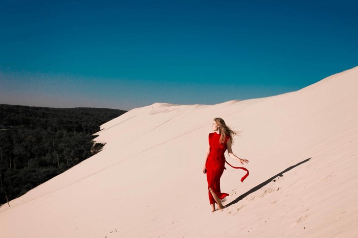 Woman in red dress on sand dune