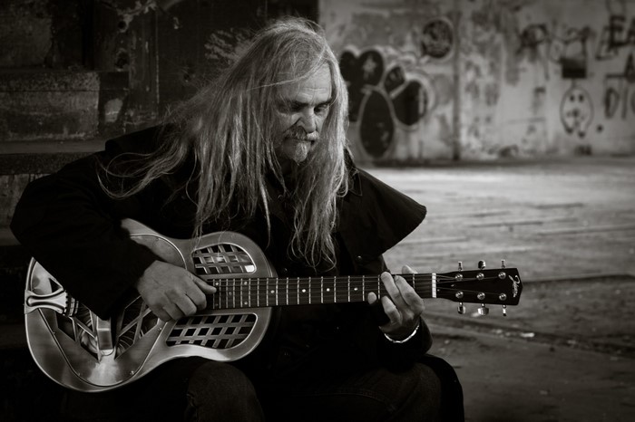 Man with long hair playing a resonator guitar