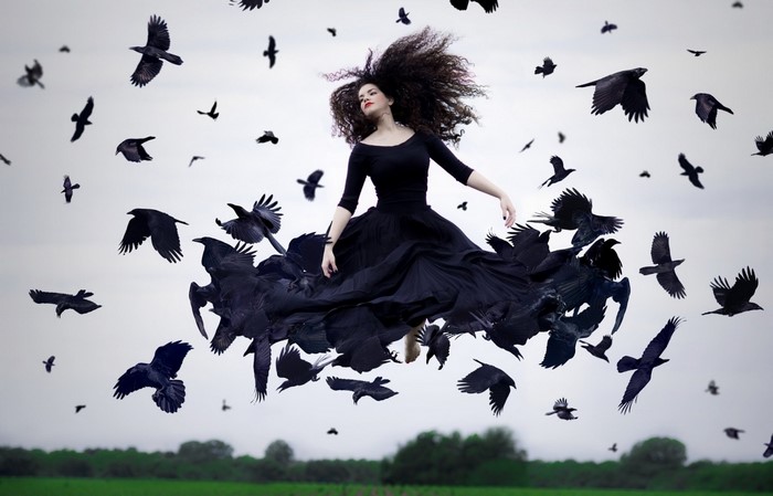 Woman in black dress with crows flying