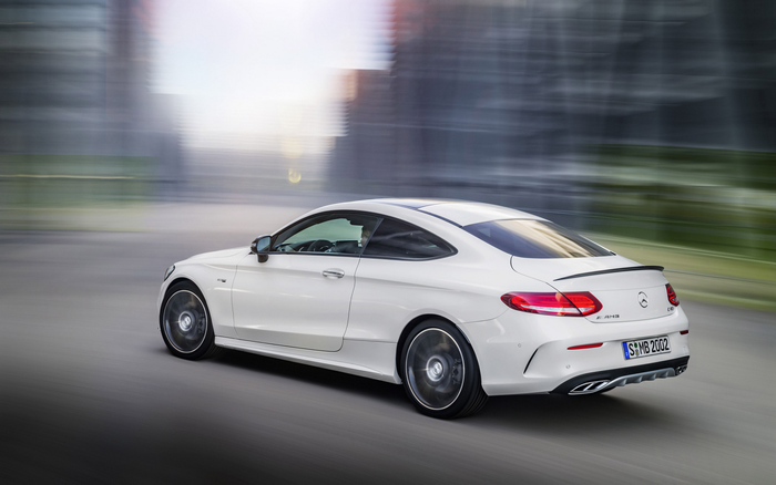 White Mercedes-Benz C43 AMG Coupe driving on a blurred street