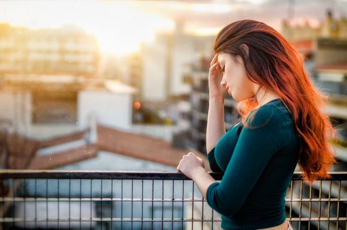 Woman with red hair on a balcony at sunset