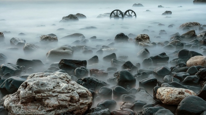 Two wheels in the mist on a rocky shore