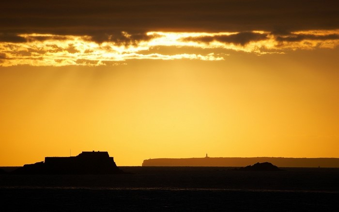 Sunset over the sea with islands and lighthouse