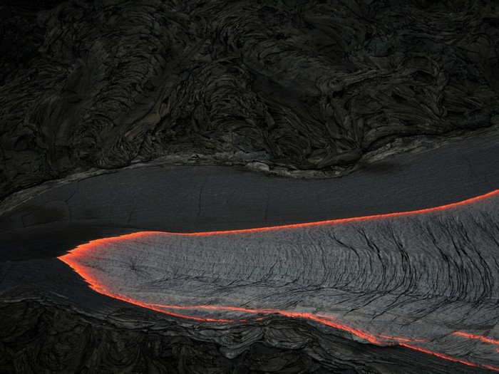 Molten lava flowing through dark volcanic rock formations
