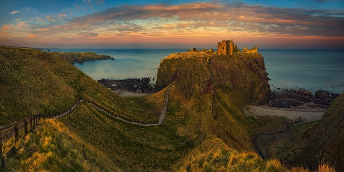 Dunnottar Castle on a cliff overlooking the sea at sunset