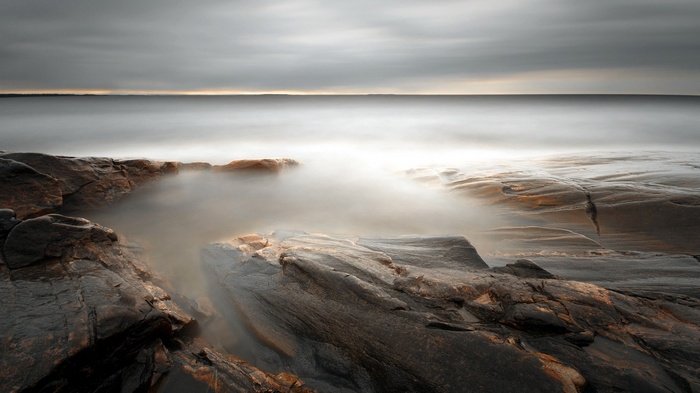 Rocky coastline with misty ocean and overcast sky