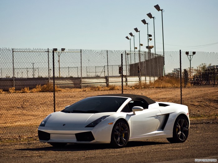 White Lamborghini Gallardo convertible parked near a fence