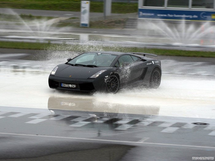 Black Lamborghini Gallardo driving through water spray