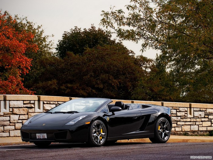 Black Lamborghini Gallardo convertible parked by stone wall