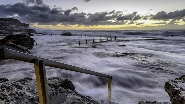 Ocean pool with railing and stormy clouds