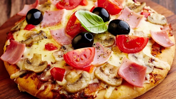 Pizza with ham, tomatoes, olives, and mushrooms