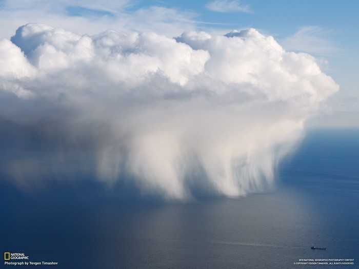 Rain cloud over the ocean with a ship